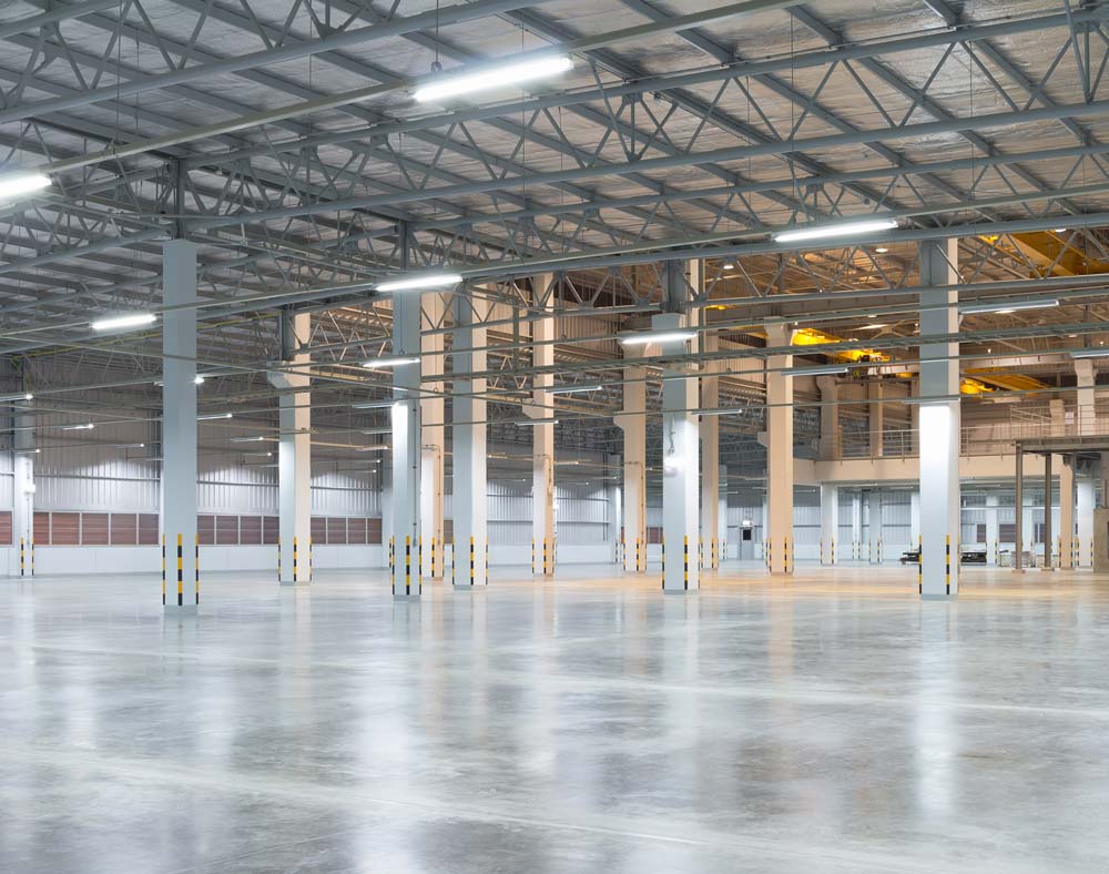 Tom fabriksbyggnad eller lagerbyggnad med betonggolv för industribakgrund.