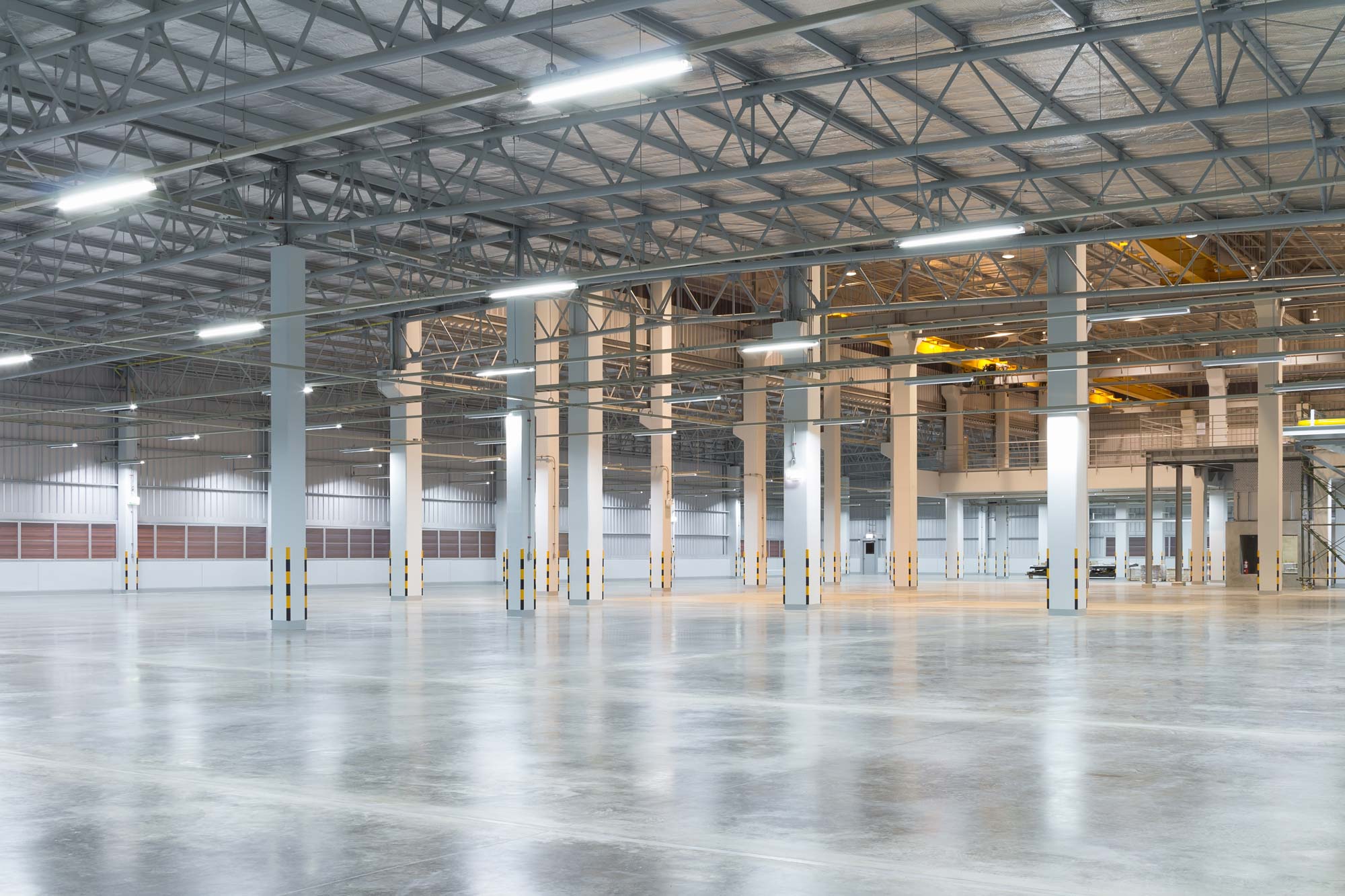 Tom fabriksbyggnad eller lagerbyggnad med betonggolv för industribakgrund.